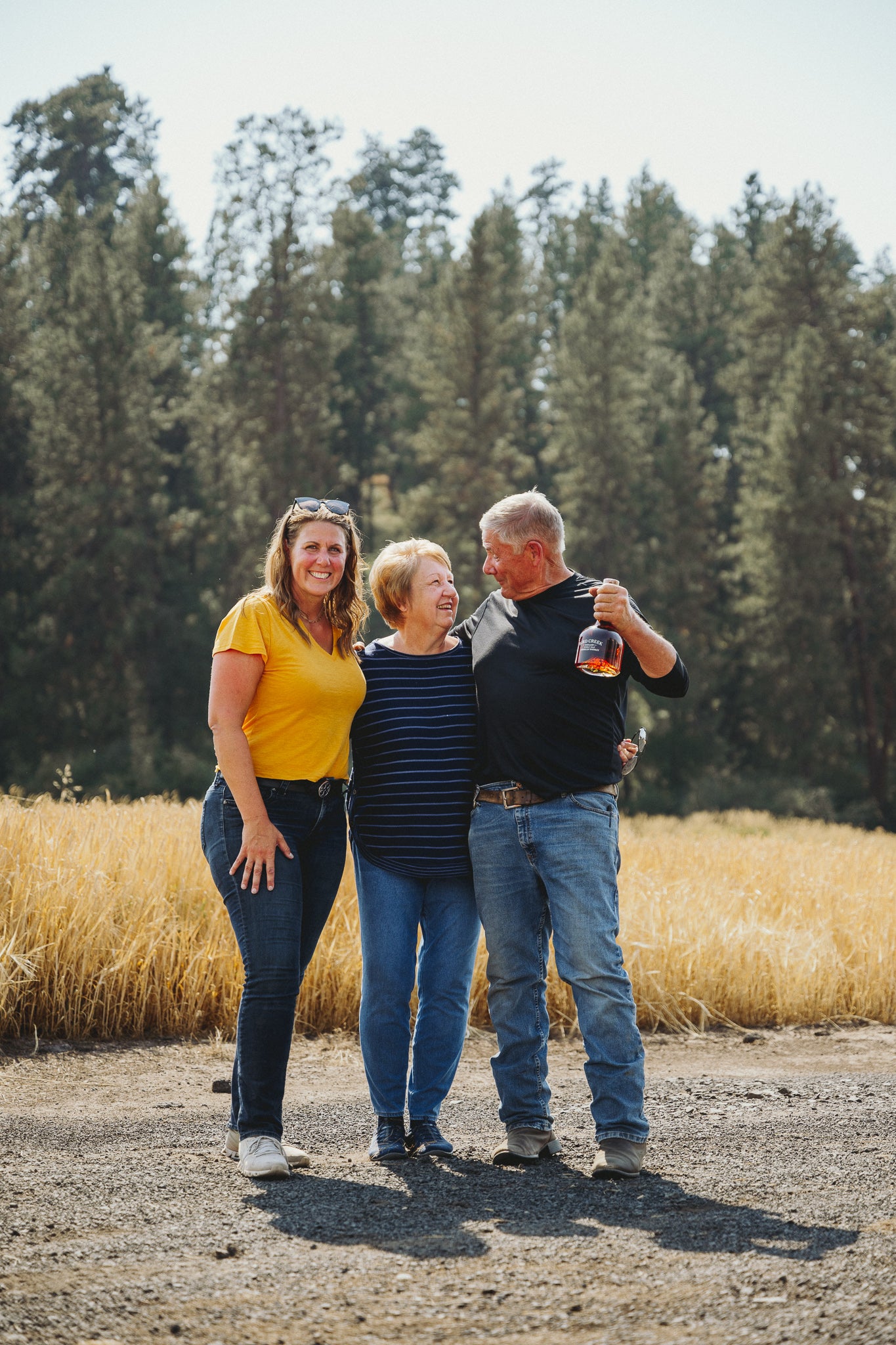 Photo of Bill Myers, and family, of Joseph's Grainery in Colfax, Washington. Bill is holding a bottle of Bird Creek Whiskey.